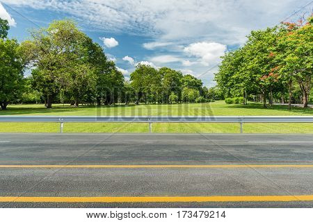 Side view of asphalt road with green grass field in park