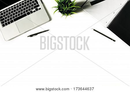 White office desk frame with laptop keyboard and supplies. Laptop, notebook, pen, clips, pencil, plant and office supplies on white background. Flat lay, top view, mockup