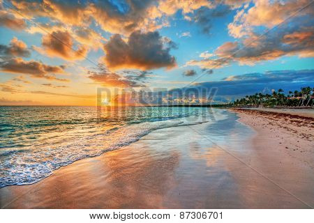 Bright and dynamic sea beach sunrise with bright blue skies and colorful clouds