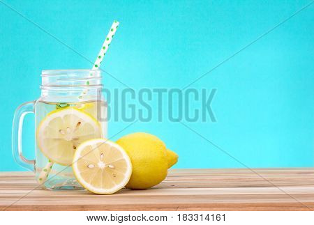 Citrus lemonade water with lemon sliced healthy and detox water drink in summer on wooden table with blue lighten background