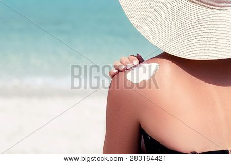 Woman Applying Sunscreen Creme On  Tanned  Shoulder. Skincare. Sun Protection Sun Cream. Bikini Hat 