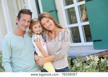 Portrait of happy family standing in front of house