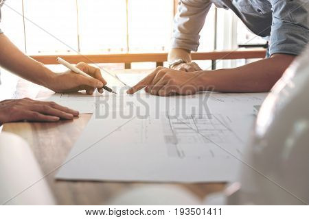 Image of engineer or architectural project Close up of Architects engineer's hands drawing plan on BluePrint and discussing to partner with Engineering tools on workplace Construction concept.