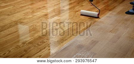 Lacquering Wood Floors. Worker Uses A Roller To Coating Floors. Varnishing Lacquering Parquet Floor 