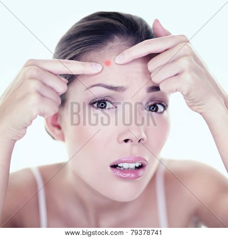 Acne pimple skin blemish spot skin care girl. Beauty care girl pressing on skin problem face. Woman with skin blemish looking at mirror isolated. Beautiful young Asian Caucasian female model.