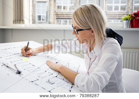 Young female architect working on blueprint