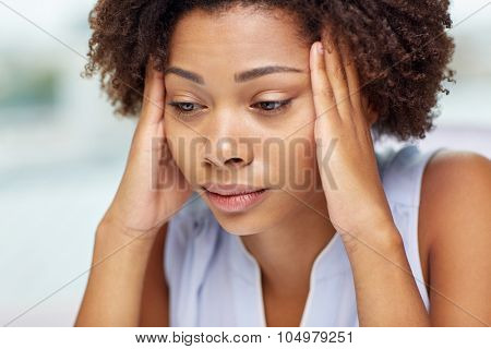 people, emotions, stress and health care concept - unhappy african american young woman touching her head and suffering from headache