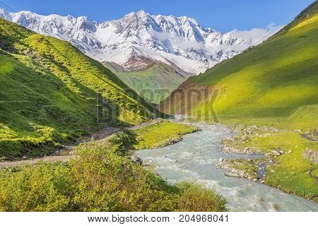 rough mountain stream and snow-capped peaks of the Caucasus Mountains in Upper Svaneti, Greater Caucasus Mountain Range in Georgia