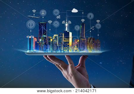 Waiter hand holding an empty digital tablet with Smart city with smart services and icons internet of things networks and augmented reality concept night scene .