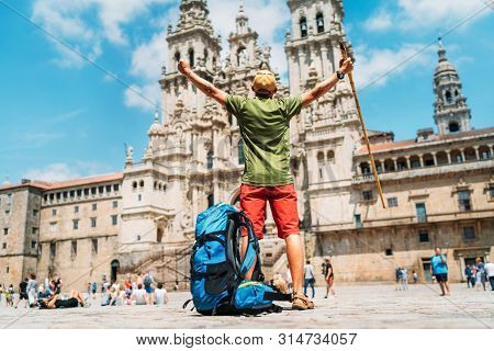 Young Backpacker Man Pilgrim Standing With Raised Arms On The Obradeiro Square (plaza) - The Main Sq