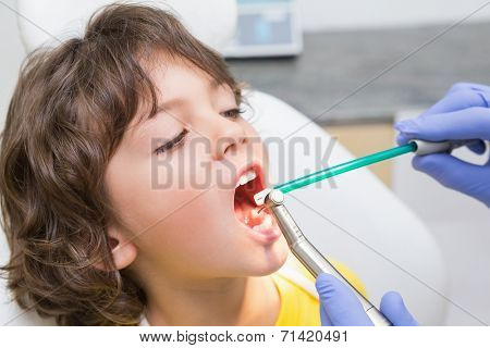 Pediatric dentist examining a little boys teeth in the dentists chair at the dental clinic