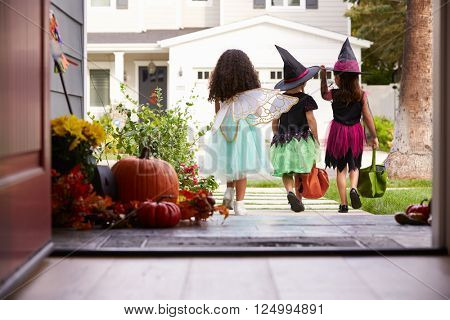 Three Children In Halloween Costumes Trick Or Treating