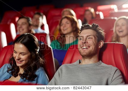 cinema, entertainment and people concept - happy friends watching comedy movie in theater