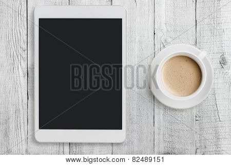 Tablet pc looking like ipad mini on table with coffee cup 