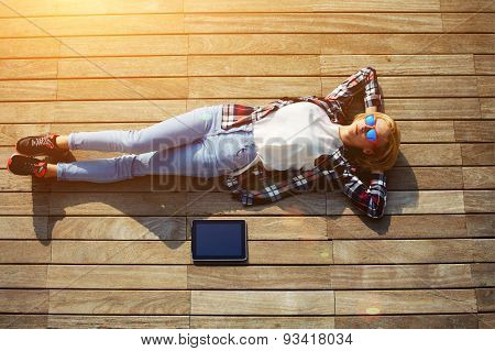 Active young tourist lying on a wooden floor with a tablet enjoying the good weather