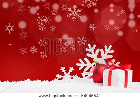 Christmas background with snow and gift box with red ribbon. White snowflakes and red xmas ball with copy space. Christmas decoration with red shiny background.