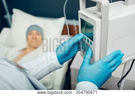 Oncologist Turning On Device Iv Drip Chemotherapy For An Elderly Woman With Cancer. Patient Receivin