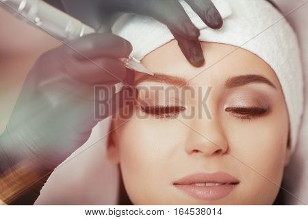 Permanent makeup. Permanent tattooing of eyebrows. Cosmetologist applying permanent make up on eyebrows- eyebrow tattoo