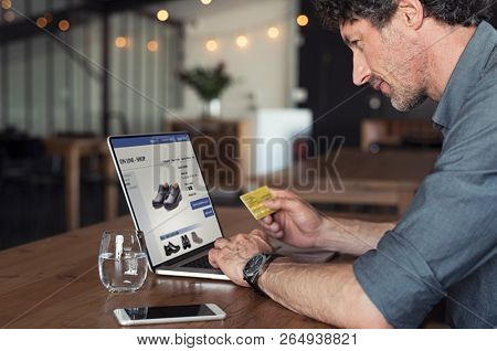 Senior businessman using debit card to make online transaction using laptop. Mature business man doing shopping online banking. Man making online payment with credit card and laptop.