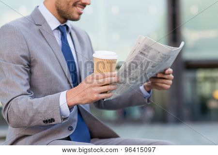 business, news, break and people and concept - close up of smiling businessman reading newspaper and drinking coffee from paper cup over office building