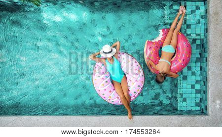 Two people (mom and child) relaxing on donut lilo in the pool at private villa. Summer holiday idyllic. High view from above.