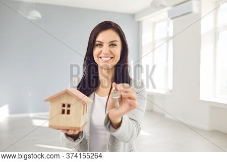 Realtor Agent Is A Realtor With Keys In Hand Against The Background Of A White Real Estate Room Apar