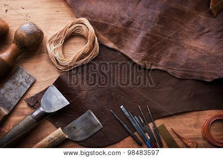 Leather craftmans work desk . Piece of hide and working tools on a work table.