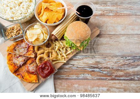 fast food and unhealthy eating concept - close up of fast food snacks and coca cola drink on wooden table