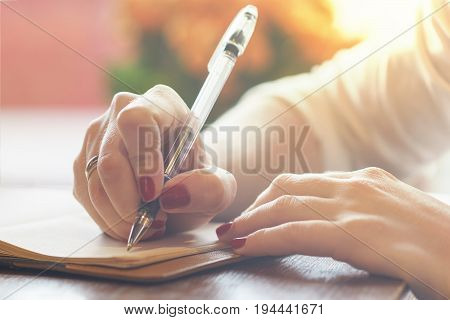 Woman's Hand With Red Nails Writing Some Message Note Or Letter To Notebook By Pen