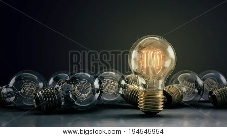 Multiple incandescent light bulbs on a reflective surface and dark background. One hero bulb illuminated standing out from the rest. Great for conveying a big idea or unique business thoughts. 3D illustration.