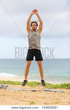 Jump Squats fitness training. Athlete Man doing Jump Squat exercise workout. Male fitness instructor training on beach.