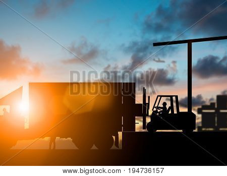 Silhouette Forklift truck lifting cargo container on a truck in the warehouse over blurred natural background sunset pastel.Business Logistics and Transportation concept.