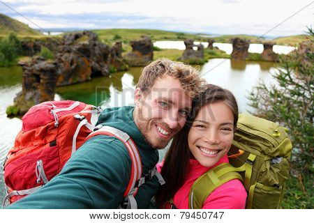 Selfie - travel couple on lake Myvatn Iceland. Friends taking selfies photo having fun traveling together visiting Icelandic tourist destination landmarks. Lake Myvatn lava columns, Iceland.