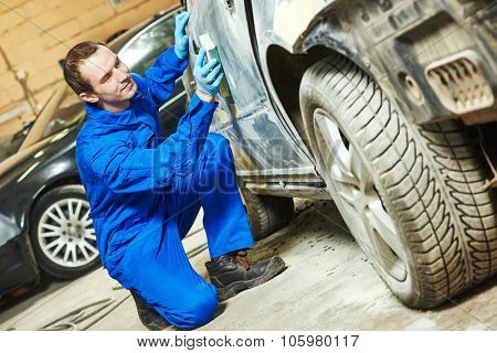 auto mechanic worker sanding car body at automobile repair and renew service station shop by sandpaper