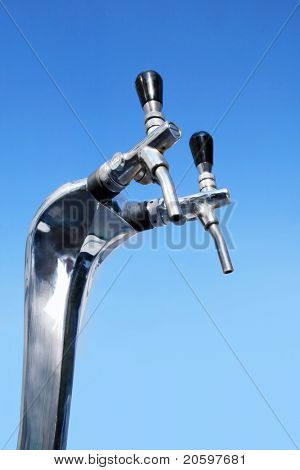 Close up of a beer tap against deep blue sky.