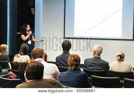 Business Conference. People Sitting Rear And Woman Speaking At The Screen