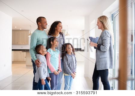 Female Realtor Showing Family Interested In Buying Around House