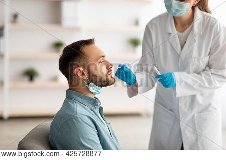 Covid Diagnostic Procedure. Doctor Making Nasal Pcr Test For Young Caucasian Man, Using Sterile Swab