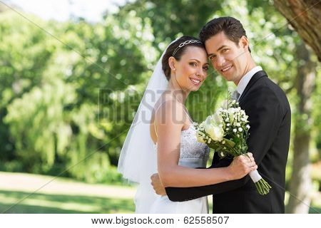 Portrait of loving newly wed couple with head to head standing in garden