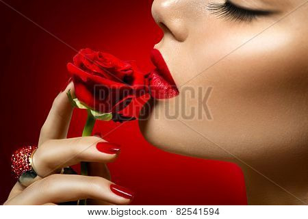 Beautiful Model woman kissing red rose flower. Red Lips, Nails and Rose. Beauty Girl. Makeup and Manicure. Sensual Mouth. Sexy Red Color Lips. St. Valentine's Day design. Part of Face