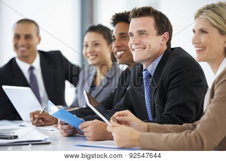 Group Of Business People Listening To Colleague Addressing Office Meeting