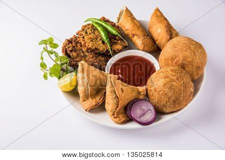 coriander vada or kothimbir vada, samosa, kachori, daal vada on brown wooden planks. indian assorted snacks. Indian snacks combination. Indian snacks group, indian favourite snacks, asian spicy snacks