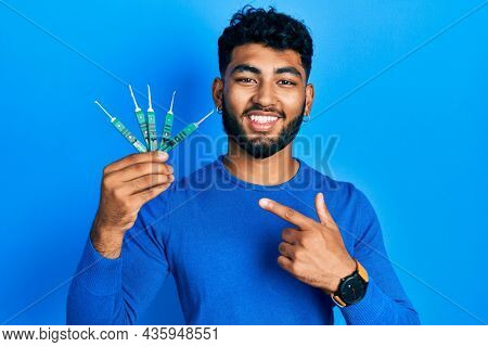 Arab man with beard holding picklock to unlock security door smiling happy pointing with hand and finger 