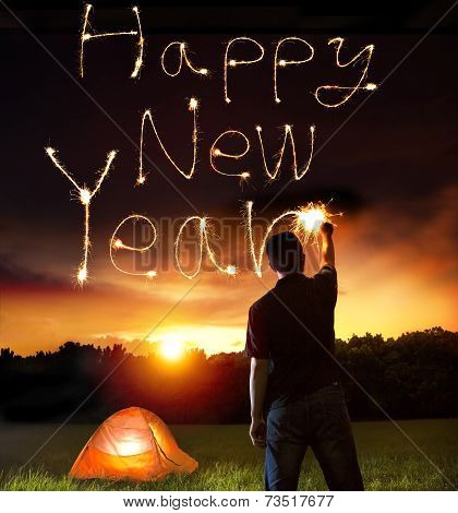 Young Man Drawing Happy New Year Words By Sparkling Stick.