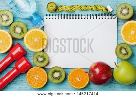 Diet plan, menu or program, tape measure, water, dumbbells and diet food of fresh fruits on blue background. Weight loss and detox concept, top view, flat lay.