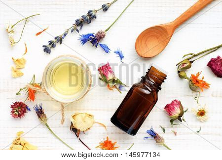 Essential oil, medicinal plant mix, herbal skincare ingredients. Top view Aroma dropper bottle, dried leaves,flowers,herbs, extract sample,spoon.