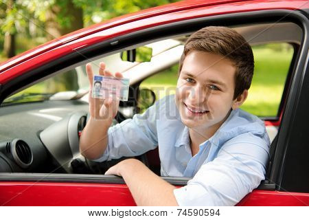 teenager sitting in new car and shows his drivers license