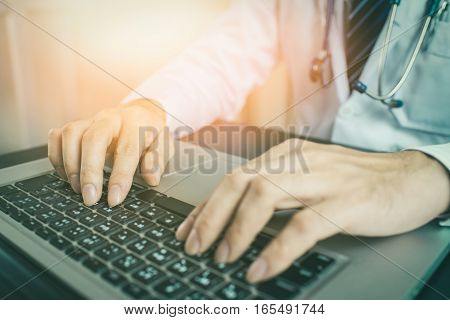 Close-up of a medical worker typing on laptop vintage tone. Doctor using laptop. Doctor using internet. Doctor using keyboard. Doctor using computer. Doctor working. Uniform doctor.