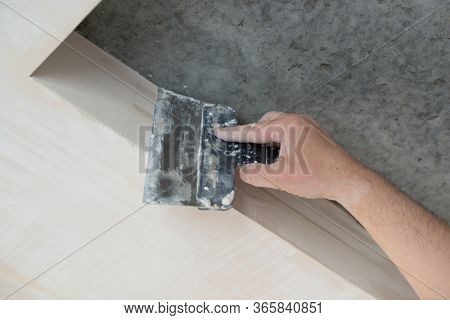 Worker putsty plasterboard ceiling in appartment, bottom view. Repairman works with plasterboard, plastering dry-stone wall, home improvement. A man makes repairs at house. Putty knife in male hand