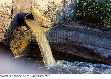 Wastewater Sewage Pipe Dumps The Dirty Contaminated Water Into The River. Water Pollution, Environme